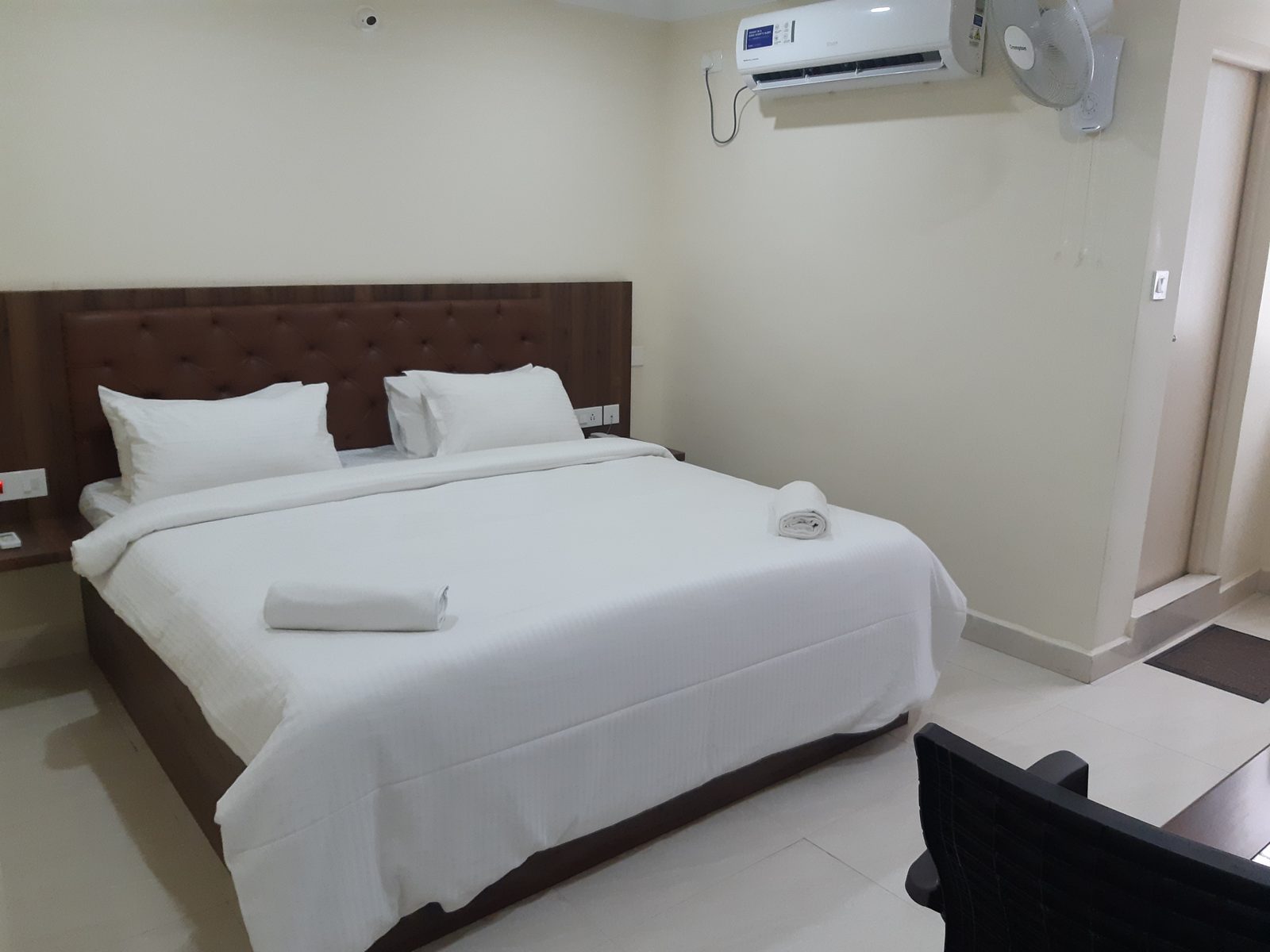 Deluxe A/C room with a king bed, air conditioner and wall fan
